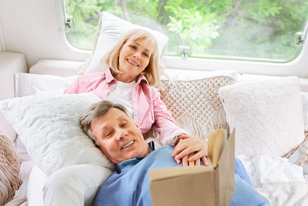 Older couple relaxing on a bed in a RV by a window